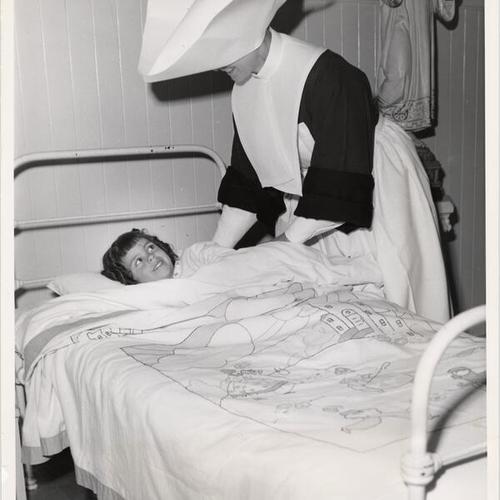 [A nun putting a child to bed at Mount St. Joseph Orphanage]