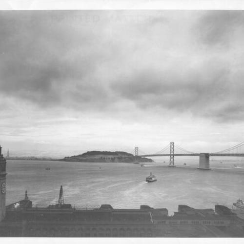 [View looking east with the Ferry building tower in the foreground and the Bay Bridge, Yerba Buena, and Treasure Island in the background]