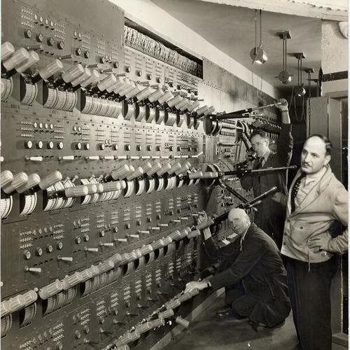 [Stage director Armando Arnini and two electricians operating the electrical switchboard at the War Memorial Opera House]