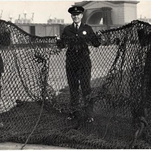 [Policeman George Badger and two other officers holding a net]