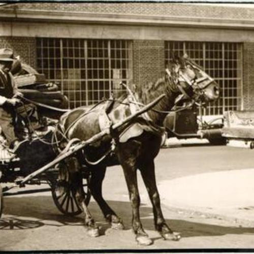 [Horse drawn vehicle stopped next to a water trough]