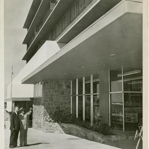 [Two men standing outside of the Stonestown Medical and Dental Center]