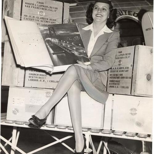 [Stewardess Momi Harrison showing one of sixty bound albums containing San Francisco scenes and Mayor Lapham's invitation to the United Nations organization to make its headquarters by the Golden Gate]