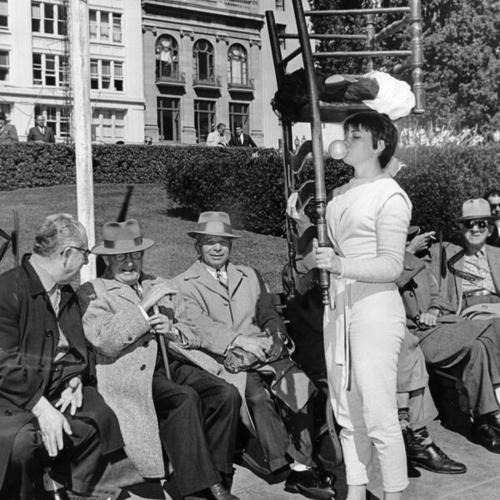[Actress Lynn Palmer wears an upside down chair on her head in Union Square to promote her theater group's new play]