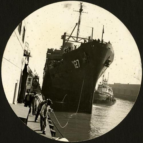 [Longshoremen at work pulling the lead line to the mooring hawser of the Navy transport Admiral Sims]
