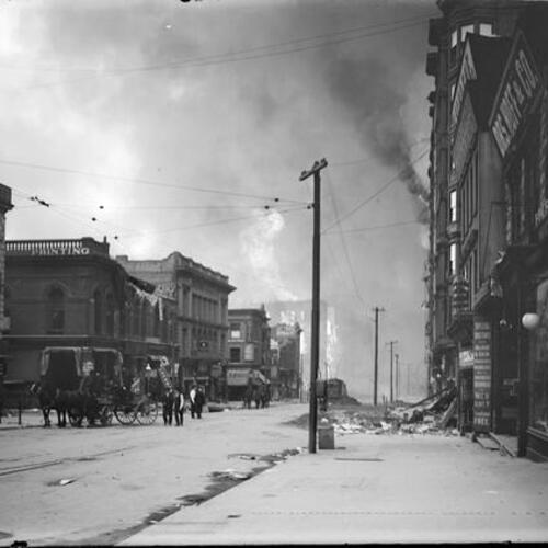 [Several people stand by as fire burns after the 1906 earthquake]