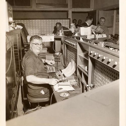 [Man working at the new radio broadcasting console in the Communications Room in Old Hall of Justice]