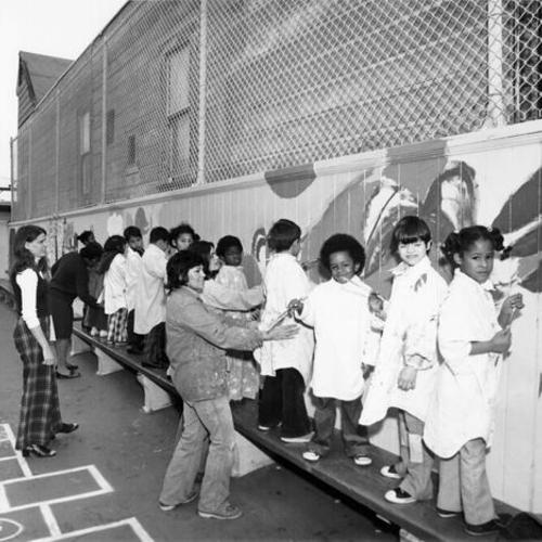 [Students painting a mural in the playground of John Muir School]