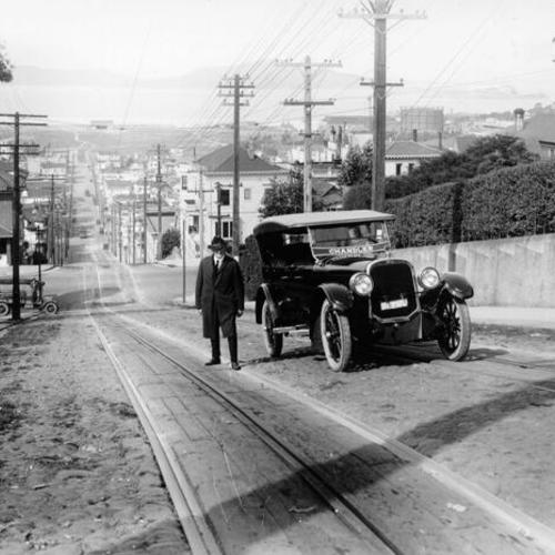 [Man standing next to parked car on Fillmore Street hill]