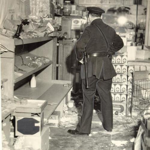 [Police officer examining store damaged during strike]