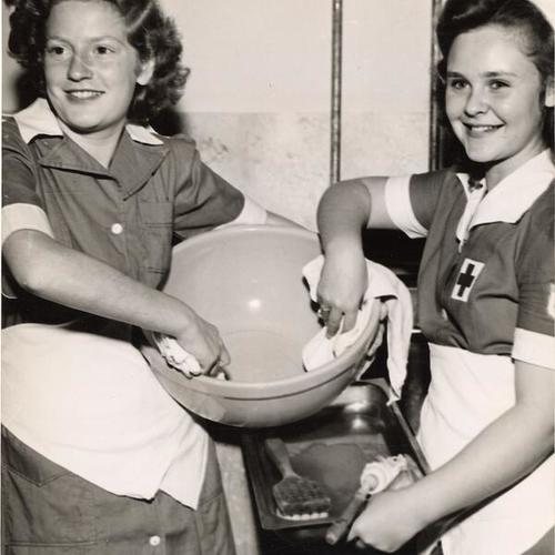 [San Francisco Camp Fire Girls Rosalie Coblentz and Patty Lou Frank participating in the 'clean-up squad' of the Red Cross Canteen]