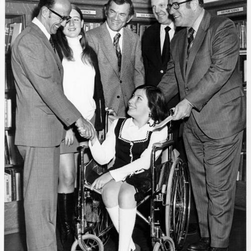 [Student in a wheelchair receiving a scholarship from a group of men at Mission High School]