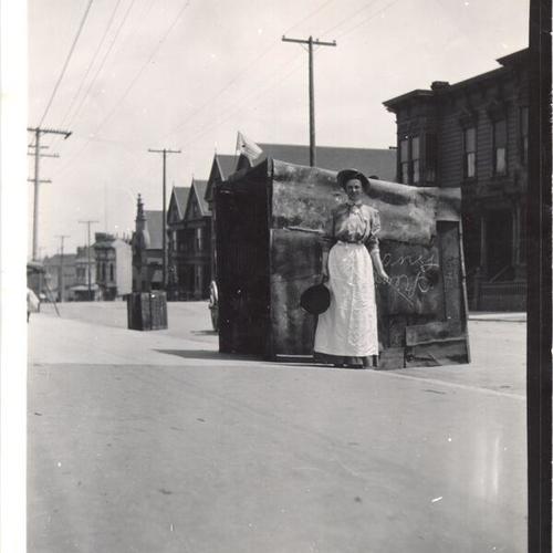 [Woman with a frying pan standing next to a street kitchen]
