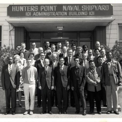 [Group of unidentified people posing in front of the Hunters Point Naval Shipyard Administration Building[
