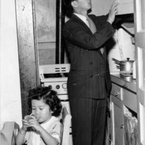 [Henry Wong and his daughter Beverly shown in cramped living quarters]