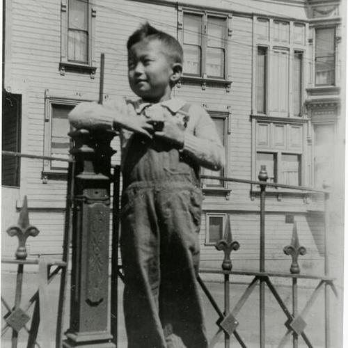 [A boy standing next to an iron fence on Octavia Street in 1931]