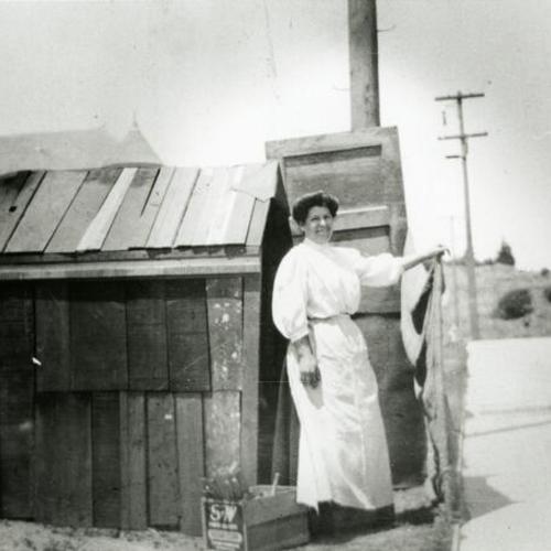 [Portrait of a woman standing next to a shed]