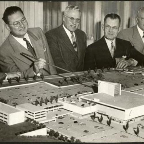 [Welton Becket, Robert Mason, Ellis Stoneson, E. C. Lipman, Henry Stoneson and an unidentified man looking at a model of Stonestown Shopping Center]