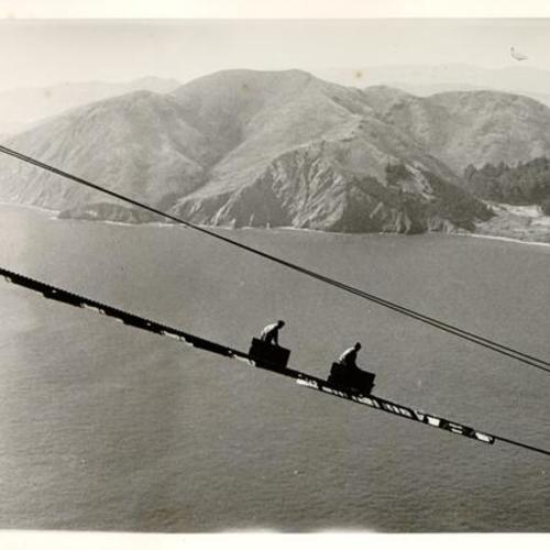 [Workers building catwalks during construction of the Golden Gate Bridge]