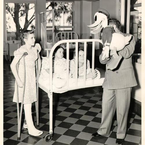 [Man with a Donald Duck doll entertaining patients at Shriners' Hospital for Crippled Children]