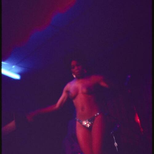 Striptease artist performing on stage with band in background