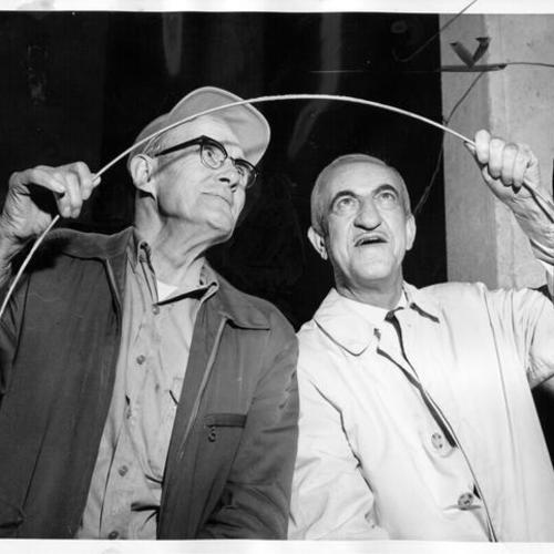 [Oscar Parker and Daniel F. Del Carlo examining a piece of removed cable strand from Golden Gate Bridge]