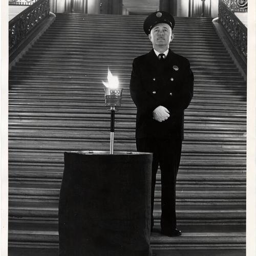 [Officer standing guard over the Olympic flame in Rotunda of City Hall]