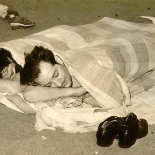 [Two people sleeping on Ocean Beach]