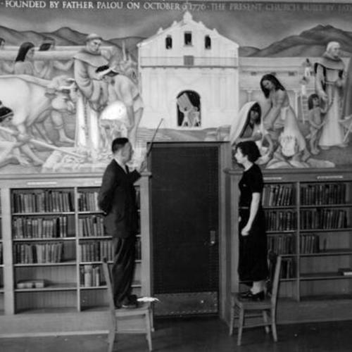[Principal William J. Drew and June Brennan admiring a new mural in the Mission High School auditorium]