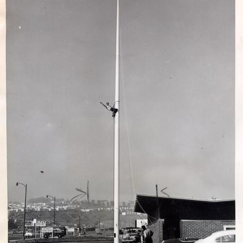 [Steeplejack James Phelan climbing a flagpole near Farmers' Market on Alemany Boulevard]