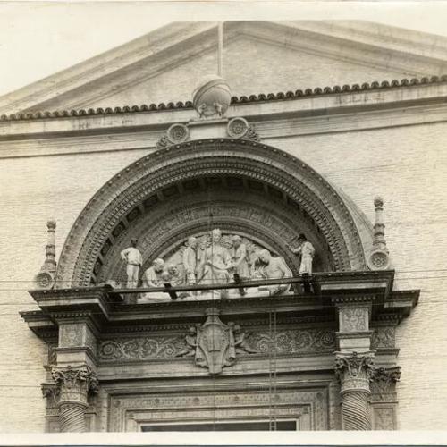 [Workmen installing a sculpture over the entrance to the Palace of Education, Panama-Pacific International Exposition]