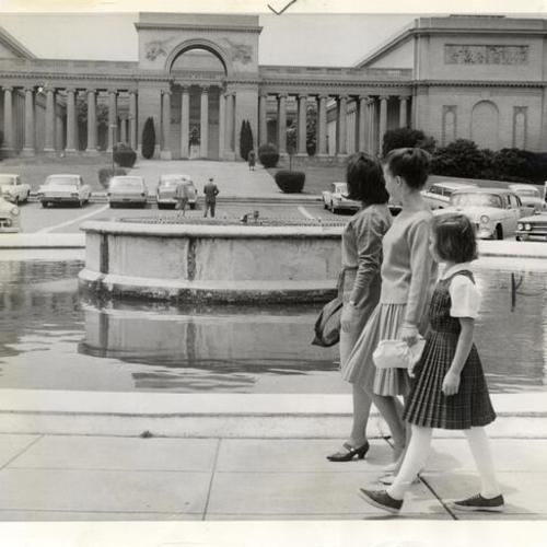 [Three people walking by the fountain across from the Palace of the Legion of Honor]