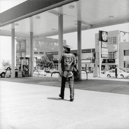 [Man in chaps at gas station at 9th and Howard Streets participating at Dore Alley Street Fair]