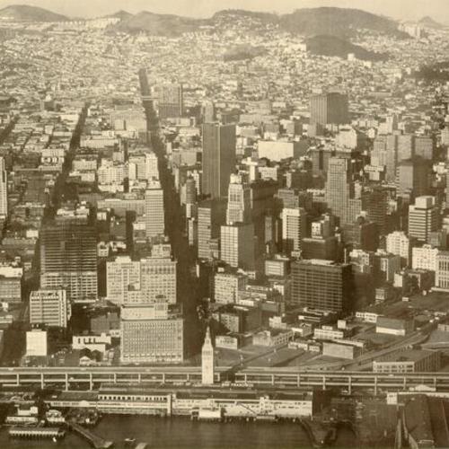 [Aerial view of San Francisco from over the bay, looking west up Market Street]