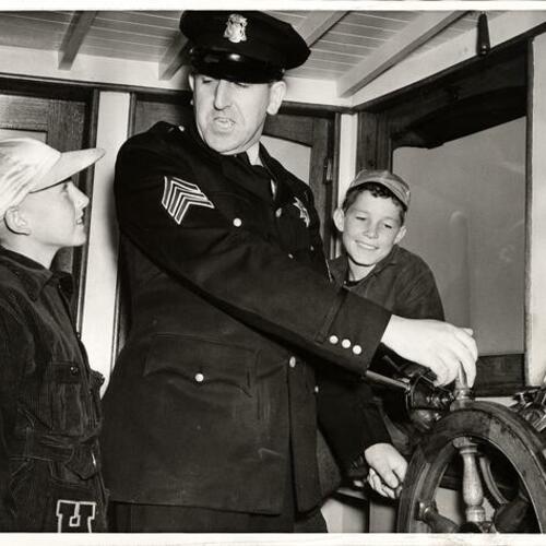 [Sergeant John Meehan (center) demonstrating to two youngsters how police boat "D. A. White" operates]