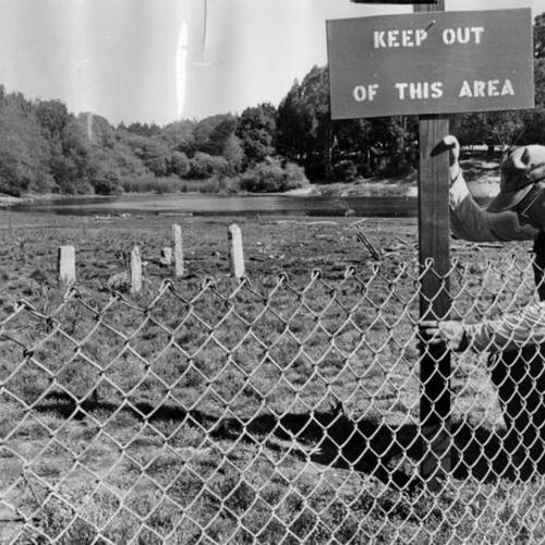 [City employee John Poppin posting a warning sign at Mountain Lake]