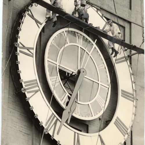 [Three men repainting the Ferry Building clock]