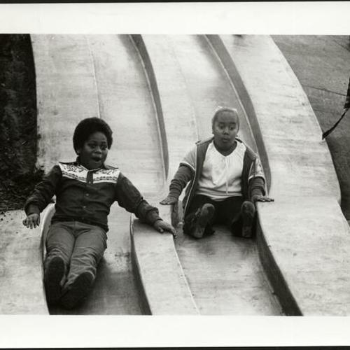 [Children ride down a slide in the Children's Playground at Golden Gate Park]