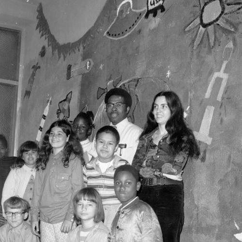 [Students, counselor, and parent volunteer standing in front of space mural in the shed area of Sir Francis Drake Elementary School]