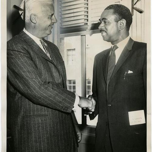 [British Consul General L.F.L. Pyman shakes hands with Dr. Carlton Goodlett