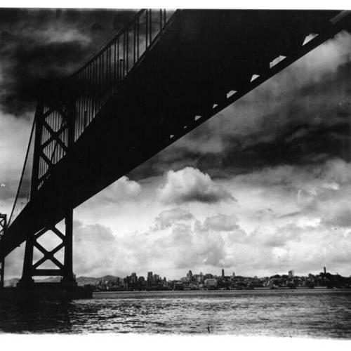 [Suspension section of Bay Bridge is silhouetted by storm clouds with San Francisco in background]