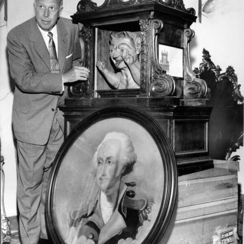 [Managing director Fay Reeder of Fox Theater stands beside old Italian relic and painting of George Washington, part the theater's surplus of antiques which may go to the highest bidder]