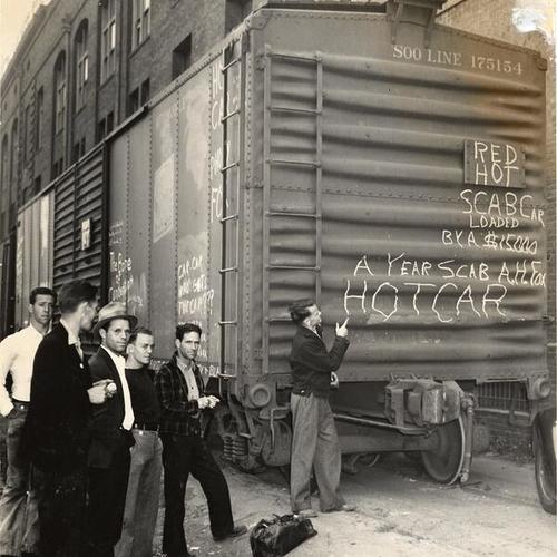 [Striking warehouse workers writing on a "hot" railroad car]