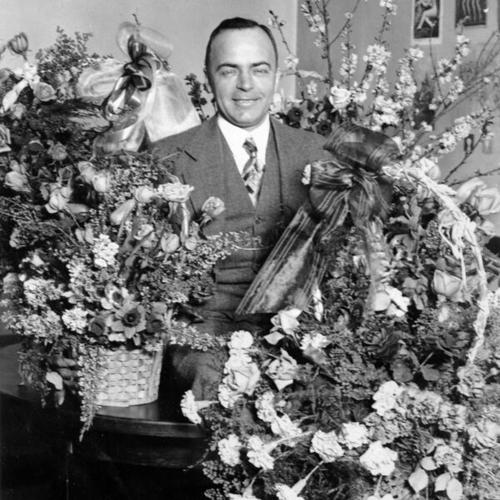 [Sylvester Andriano at home with several floral arrangements]