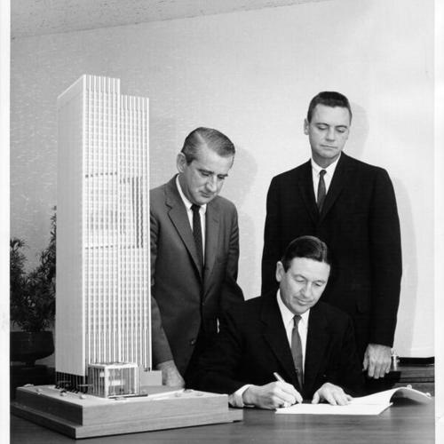 [Robert M. Haynie signing a contract for structural steel to be used in a new Wells Fargo Bank building while Fred McPherson and D. R. McCaa look on]