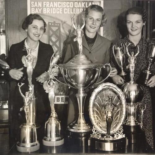 [Dorothy Petersen, Dorish Schuler, and Dorothy Buelher displaying trophies for best floats, bands, and marching units in the opening ceremony parade for San Francisco-Oakland Bay Bridge]