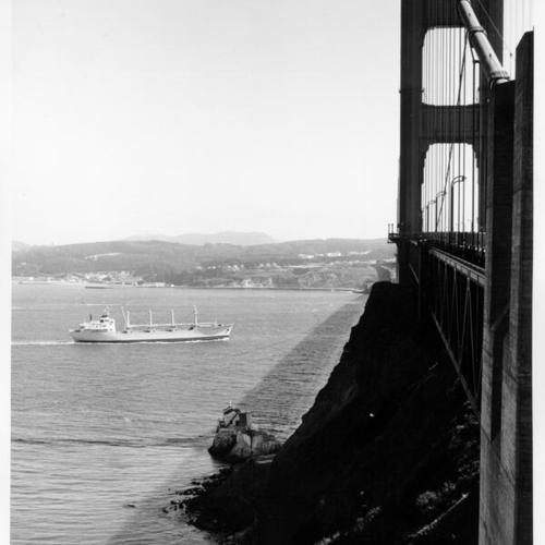 [View of a ship passing underneath the Golden Gate Bridge from near the shore of the Marin County side]