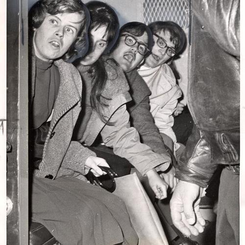 [Demonstrators in paddy wagon after being arrested at the Sheraton Palace Hotel by policemen]