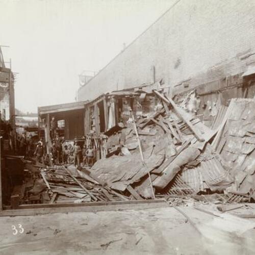 033 People with axes standing in debris of wooden building during demolition