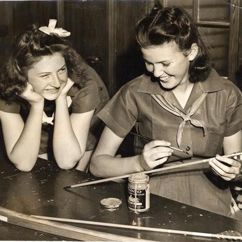 [San Francisco Camp Fire Girls Lorene Schulker and Sylvia Pommer painting their bows and arrows]